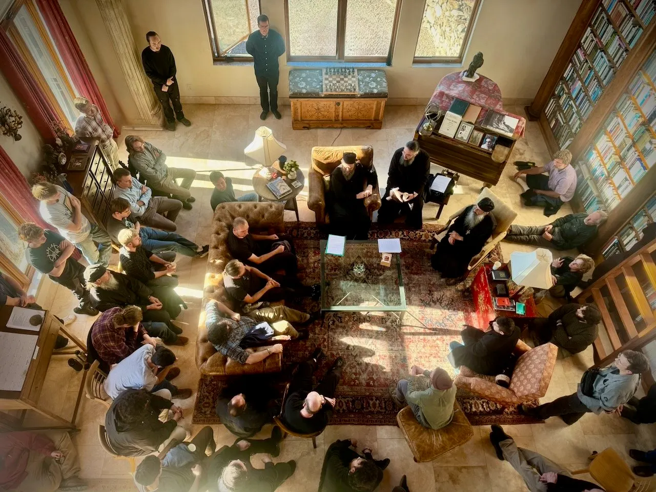 Seen from above, two abbots seated among young men gathered in the monastery library for a question-and-answer session.