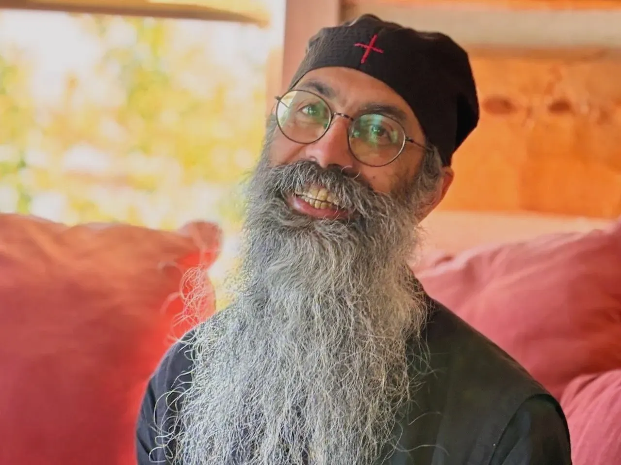 Papa Ephraim, smiling, with a long grey beard and a black monastic cap.